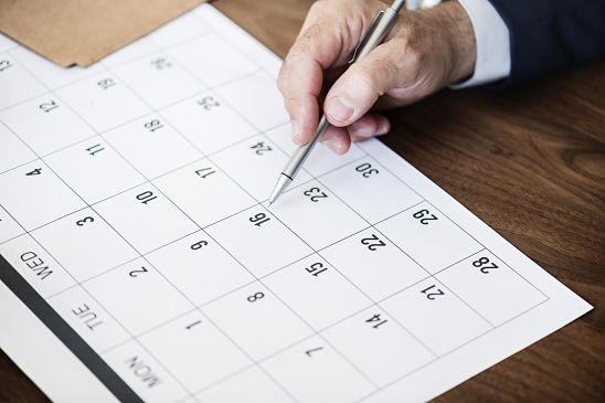 El hombre mira el calendario con la fecha de renovación de su certificado digital y tiene la intención de marcarlo con un bolígrafo.